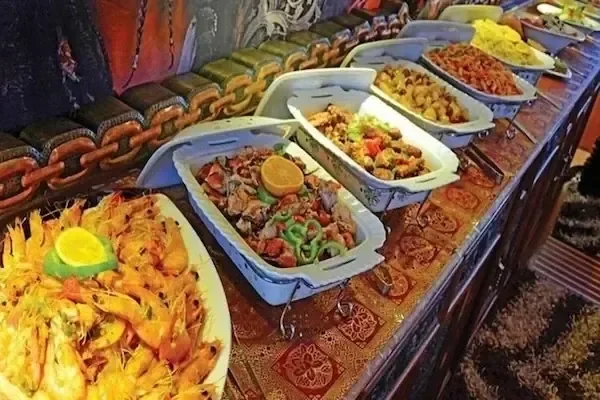 Buffet spread of seafood and Egyptian dishes including shrimp, seasoned chicken, and rice.